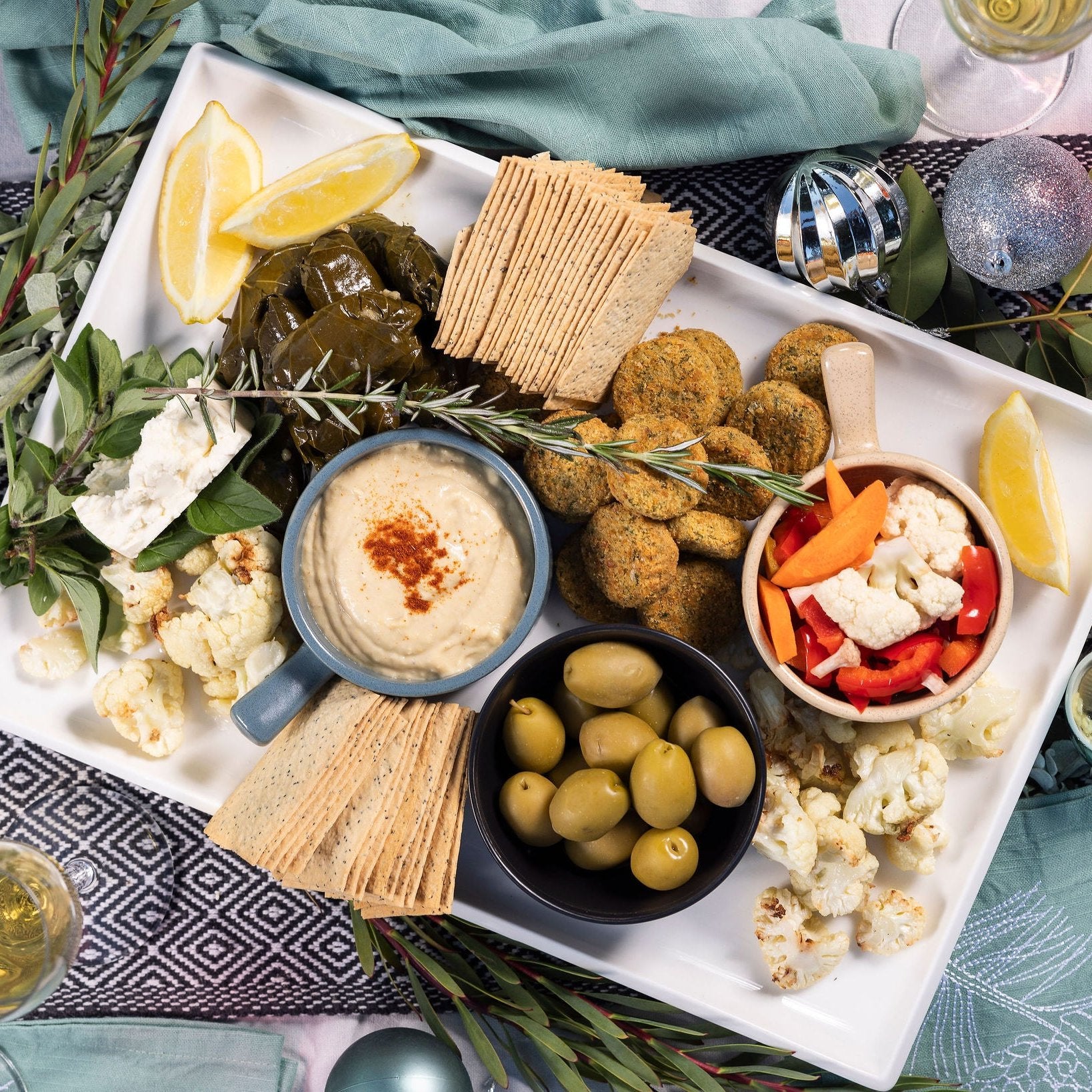 A platter of mixed savoury bites sits on a Christmas table.